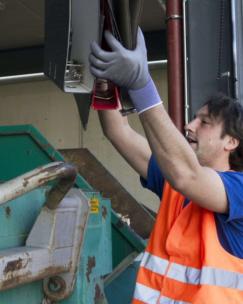 worker-at-a-waste-container-throwing-away-folders.jpg worker-at-a-waste-container-throwing-away-folders.jpg